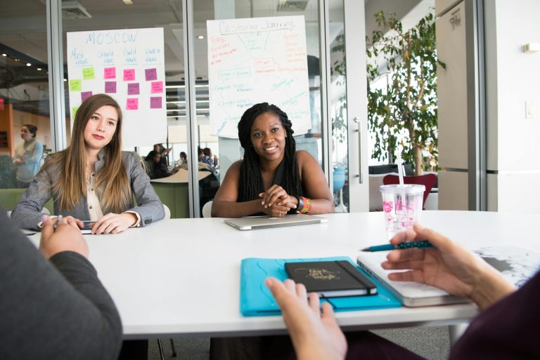 Professional team meeting with diverse group in a modern office setting, discussing project details.